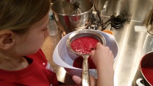 Straining raspberry puree to get out the seeds