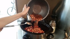 Adding the beans into the chili slow cooker.