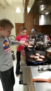 Max flipping the lamb burgers, Alex toasting pine nuts 